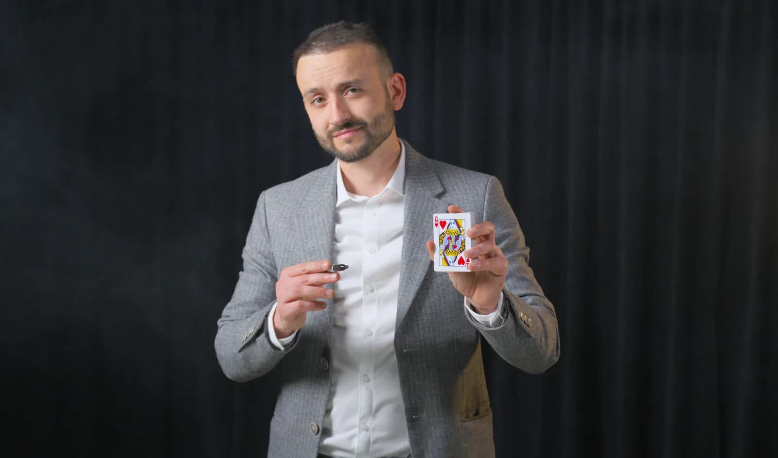 Magicien entreprise — Tyson Dumas en close-up, dame de cœur en main, costume gris (événement corporate)