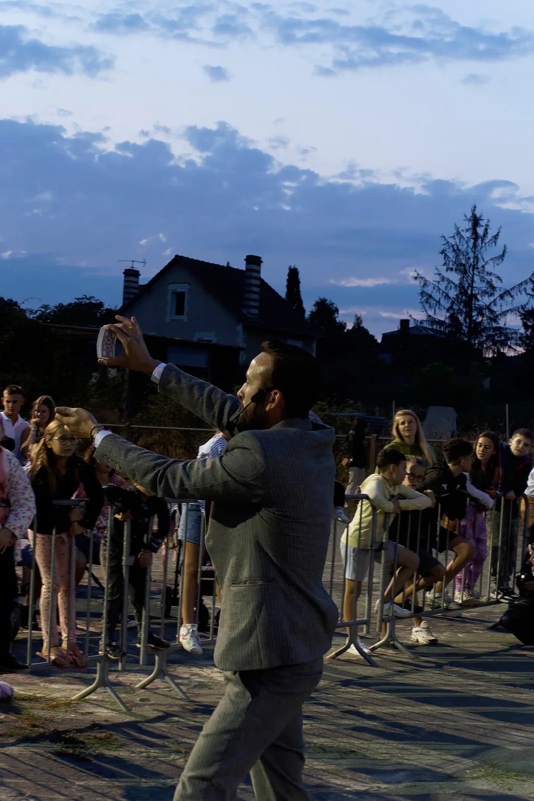 Tyson Dumas en spectacle public, micro tendu vers les spectateurs au crépuscule