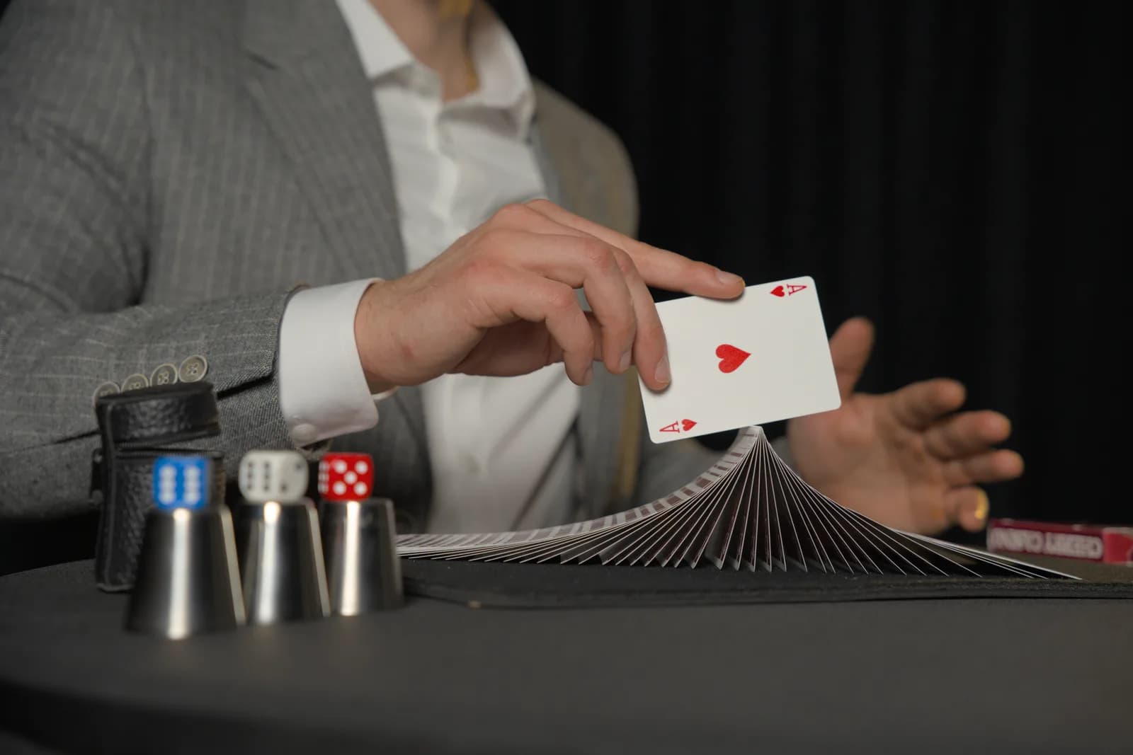 Gros plan sur les mains de Tyson Dumas présentant l'As de cœur au-dessus de son jeu de cartes déployé