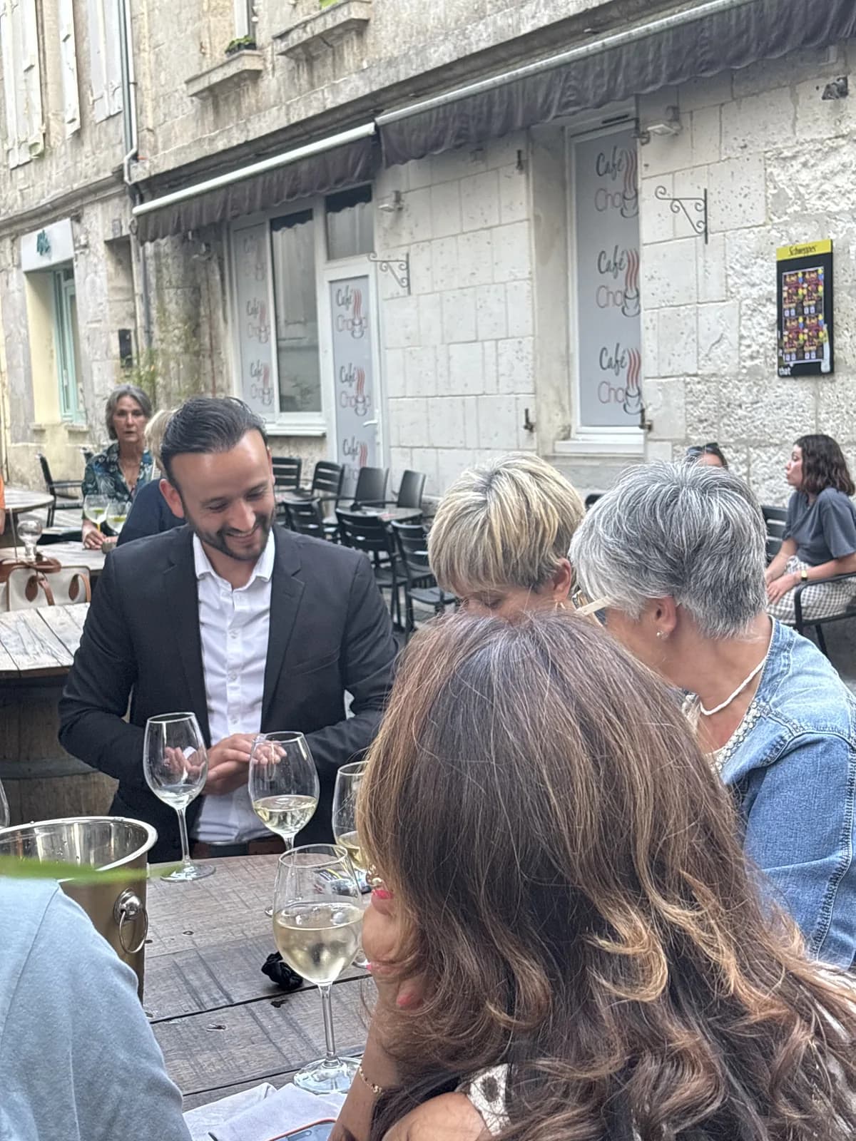 Tyson Dumas présentant une carte à un groupe de spectatrices en terrasse à Angoulême
