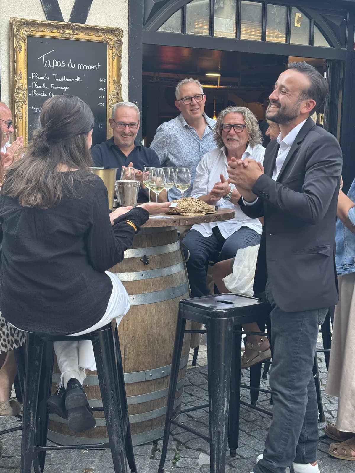 Tyson Dumas en interaction conviviale avec un groupe lors d'une prestation en terrasse au Bar Le Scénario